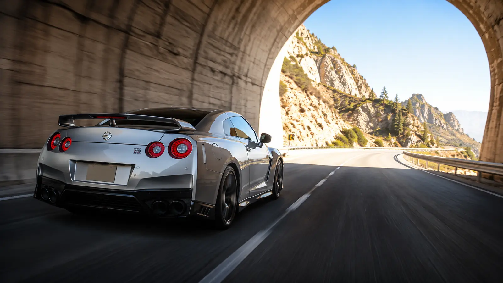 АВТО 1001394 серебристый Nissan GT-R у выхода из горного тоннеля