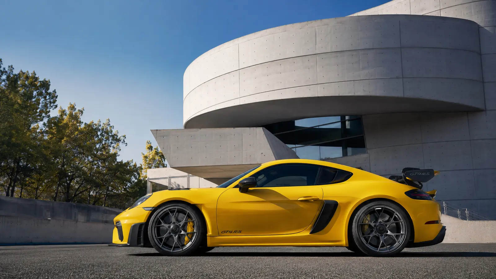 АВТО 1000901 жёлтый Porsche Cayman GT4 у бетонного музея