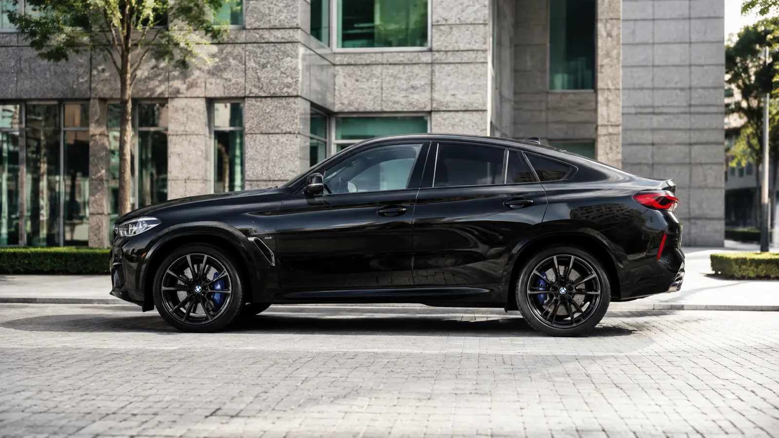 АВТО 1000662 чёрный BMW X6 M в профиль у гранитного здания