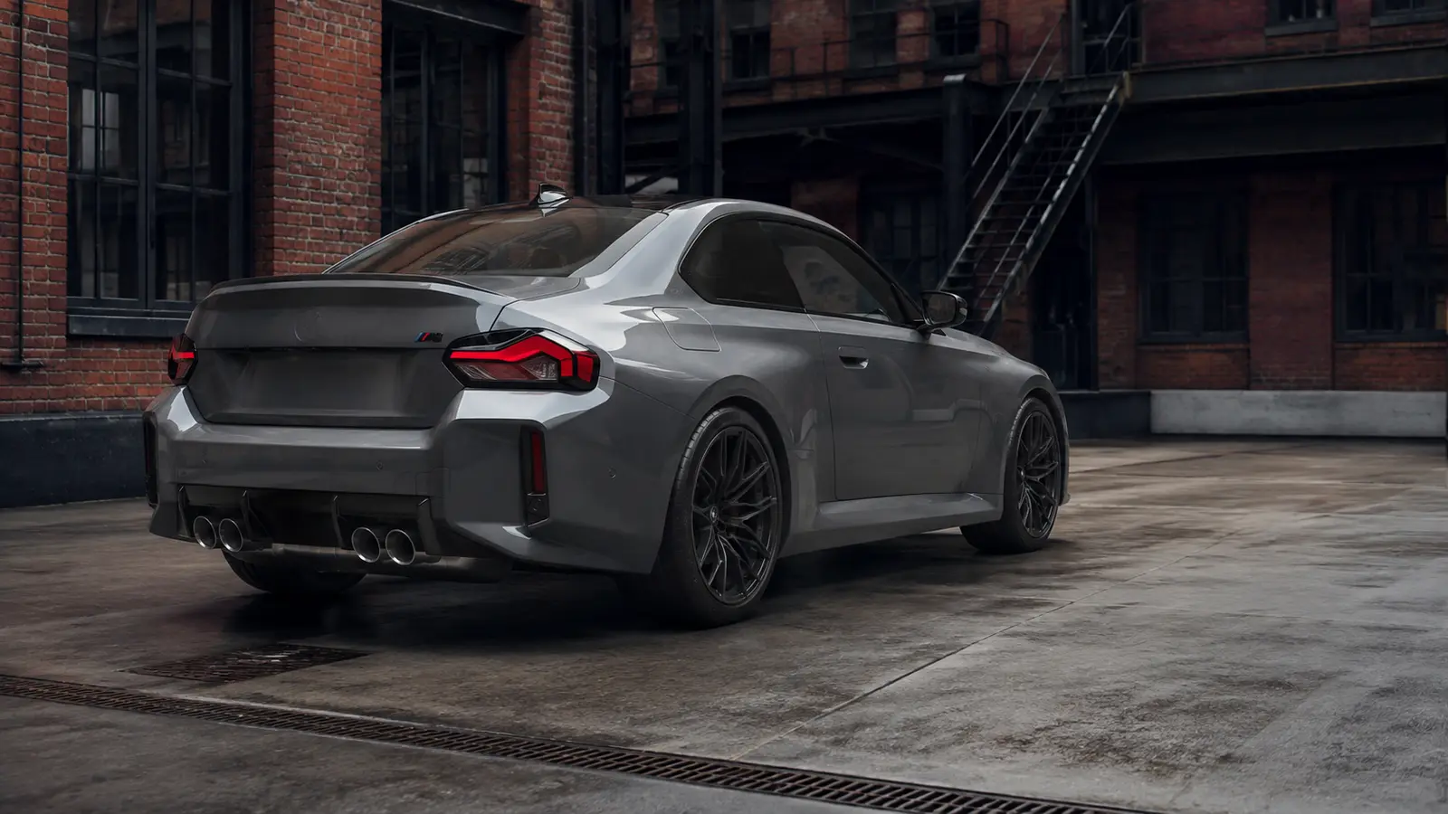 АВТО 1000681 серый BMW M2 сзади в индустриальном дворе