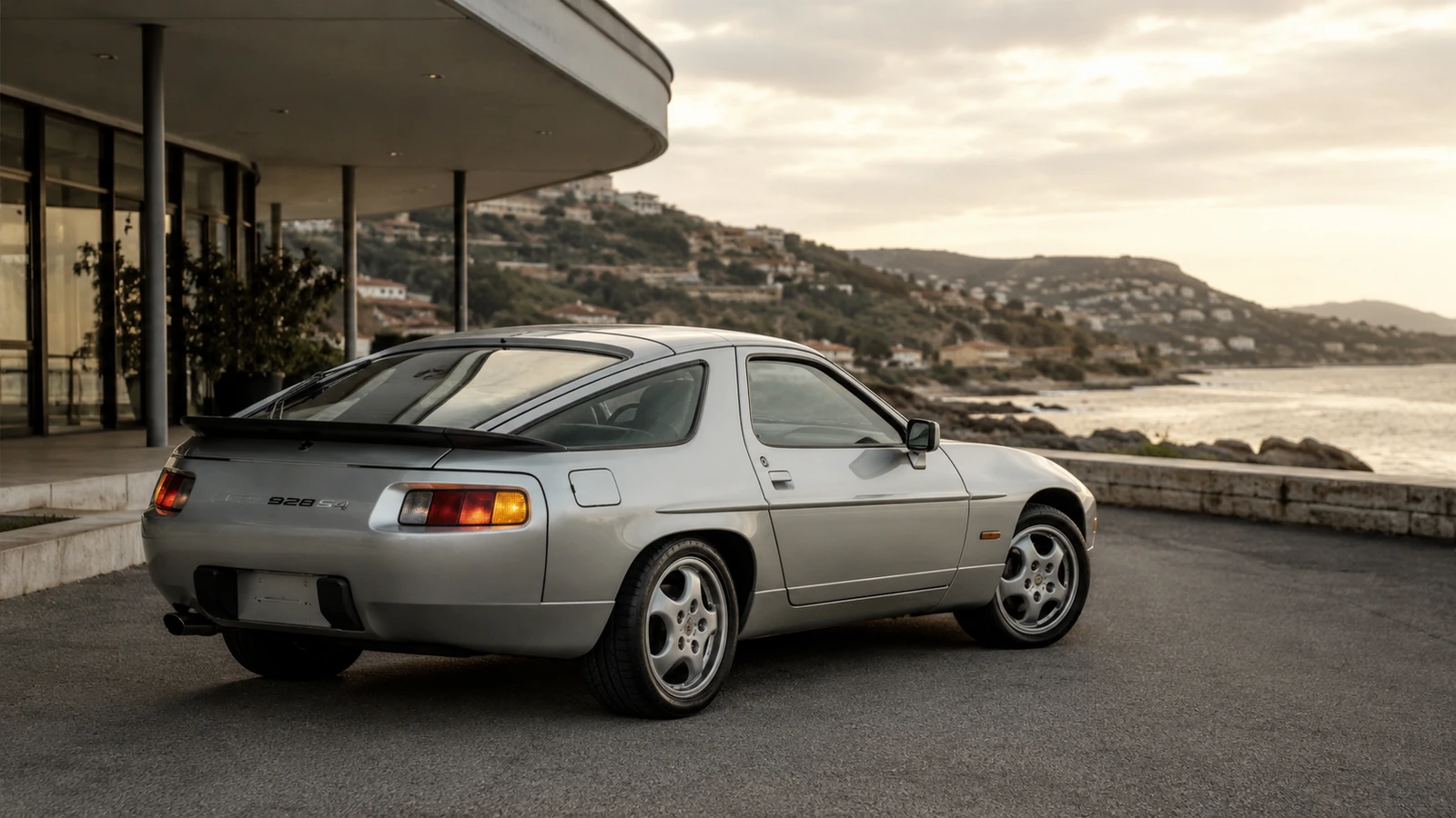 АВТО 1000759 серебристый Porsche 928 у морского отеля в стиле 80-х